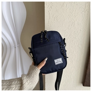 Close-up of deep blue waterproof nylon crossbody bag with Hello Weekend label