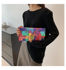 Detail of colorful geometric patchwork clutch bag with gold metal clasp on model