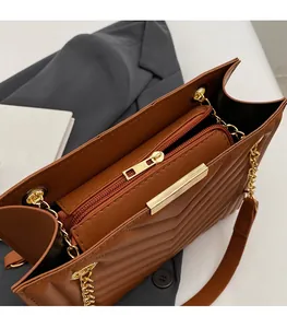 Detail of caramel brown V-quilted bag with golden zipper and chain strap texture