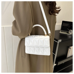 Close-up of white quilted handbag featuring unique woven handle and gold hardware detail