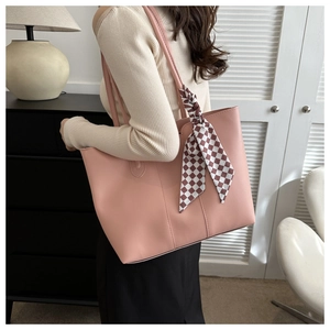 Detail of pink tote bag with checkered scarf accent shown in a minimalist room setting