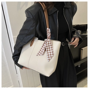 Detail of cream leather tote bag with brown handles and a checkered silk scarf accessory