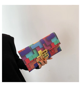 Detail view of colorful geometric patchwork clutch bag with golden metallic interlocking clasp