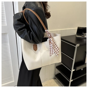 Detailed shot of cream tote bag with brown straps and a checkered silk scarf accessory