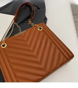Detailed close-up of brown quilted shoulder bag with golden chain and V-shaped stitching