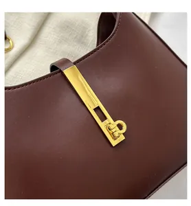 Close-up of deep brown leather bag with elegant gold metal latch and ring detail