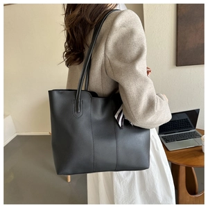 Detail of soft black PU leather tote bag with stylish striped ribbon on model's shoulder