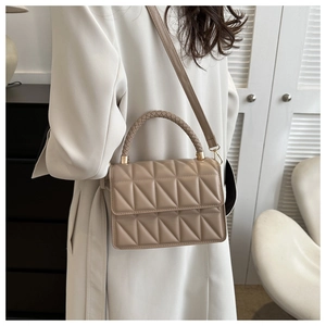 Detail of beige quilted handbag featuring woven top handle and gold-tone hardware