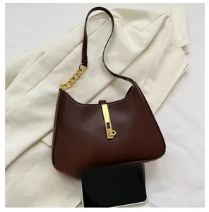 Detailed view of brown leather Hobo bag with gold lock and chain strap on blazer
