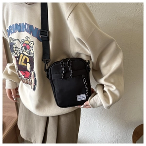 Macro detail of black nylon mini crossbody bag showing Hello Weekend tag and strap