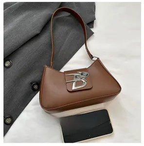Confronto dimensioni borsa baguette in pelle marrone con smartphone e fibbia argento