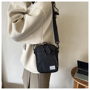 Detail of black canvas crossbody bag featuring a Hello Weekend patch and rope zipper pull