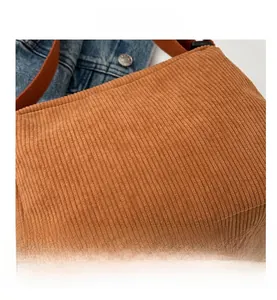 Close-up of brown corduroy crossbody bag texture with orange fabric shoulder strap