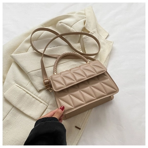 Detail of beige quilted crossbody bag with woven handle on a white blazer