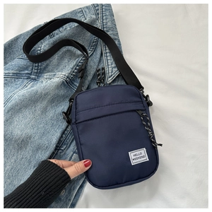 Detail of navy mini nylon crossbody bag featuring Hello Weekend label and adjustable strap
