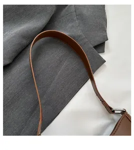 Dettaglio del manico in pelle marrone con cuciture fini e anello in metallo argentato