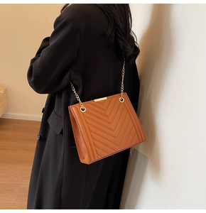 Brown quilted chain shoulder bag with V-shaped stitching shown on model for size and style