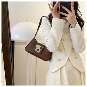 Dettaglio borsa baguette in pelle marrone con fibbia a B argentata e outfit in tweed