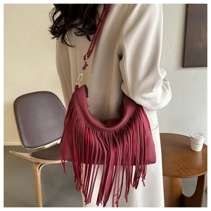 Detailed view of burgundy suede bucket bag featuring long fringe tassels and golden hardware