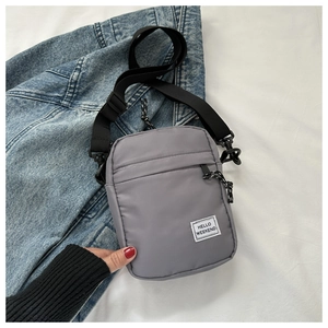 Detailed close-up of grey crossbody bag with HELLO WEEKEND label on denim jacket