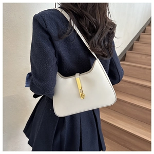 Detail of minimalist cream leather hobo bag with distinctive gold piston clasp on shoulder