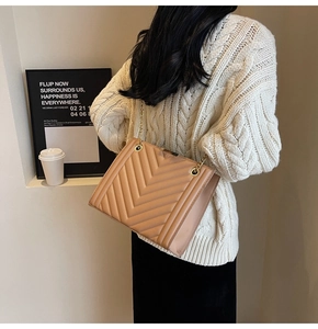 Quilted crossbody bag with gold chain strap worn over a white knitted sweater