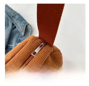 Detail view of smooth silver metal zipper and brown corduroy fabric on shoulder bag
