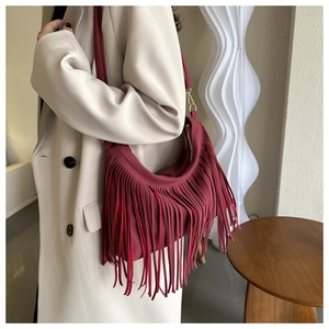 Close-up of burgundy hobo shoulder bag with long fringe tassels and matte texture
