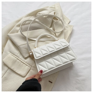 Macro detail of white quilted handbag with woven handle on professional blazer