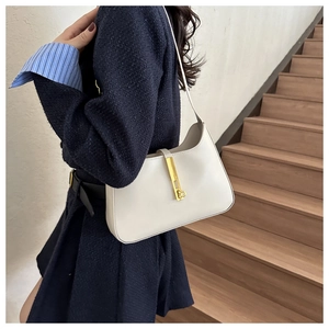 Chic beige leather hobo bag with gold metal piston buckle worn on model's shoulder