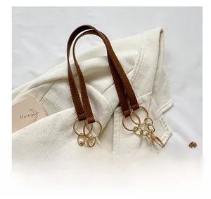 Detail of brown corduroy tote bag featuring leather handle and golden metal chain link