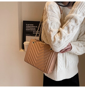 Detail of camel chevron quilted bag with golden chain straps and elegant matte texture