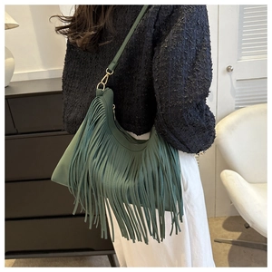Detail of dark green tassel bucket bag with matte leather and hobo bohemian style