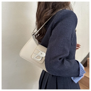 Dettaglio della borsa baguette in pelle bianca con fibbia con logo B argento su una modella