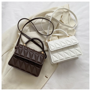 Detail of quilted rhombus texture on brown and cream crossbody bags on beige blazer