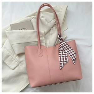 Pink faux leather tote bag with checkered scarf accent next to a blazer and arts book