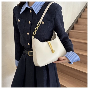 Détail du sac à bandoulière en cuir crème avec fermoir doré et bandoulière chaîne