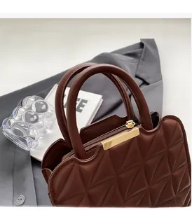 Primo piano borsa trapuntata marrone con cuciture a triangolo e dettagli dorati