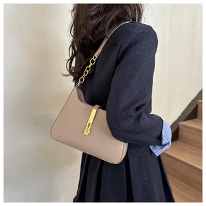 Detail of khaki leather crossbody bag with gold chain strap and vertical metal lock closure