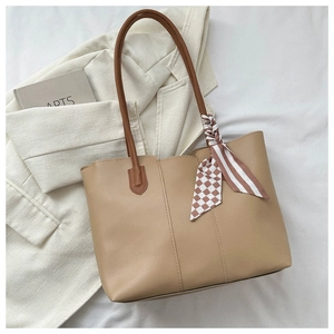 Close-up of khaki leather tote with dark brown handles and decorative striped silk scarf