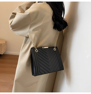 Detail of black V-quilted faux leather bag with gold chain strap and accordion side view