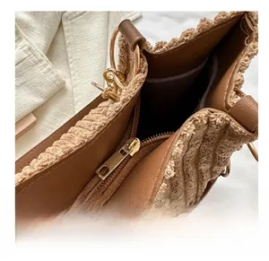 Close-up of smooth gold zipper and textured brown fabric detail on women shoulder bag