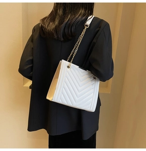 White V-quilted shoulder bag with gold chain strap shown on black blazer in a back view