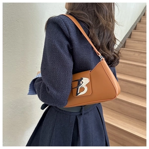 Dettaglio di una borsa baguette in pelle marrone con ornamento metallico a lettera B