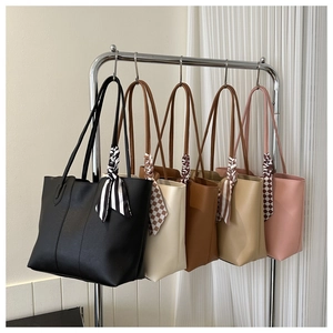 Detail of minimalist tote bags in multiple colors with decorative scarves on handles
