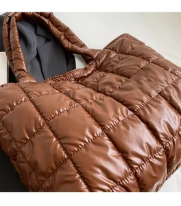 Detail of brown quilted down tote bag showing soft glossy nylon texture and padded handles