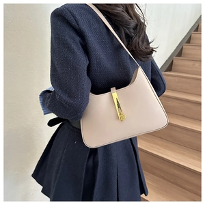 Detail of vintage beige leather shoulder bag with iconic gold piston closure on a model