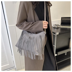 Detail of grey crossbody bucket bag featuring long fringe tassels and premium PU leather