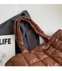 Detail of a brown quilted tote bag with wide shoulder straps and puffy checkered stitching