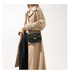 Dettaglio della borsa a tracolla in tweed nero indossata con trench beige